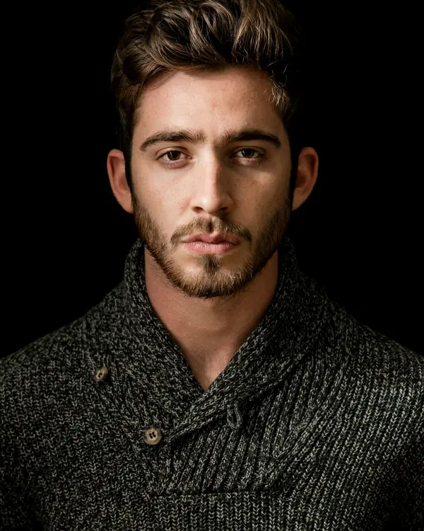 A bearded man in a knit sweater looking straight at the camera